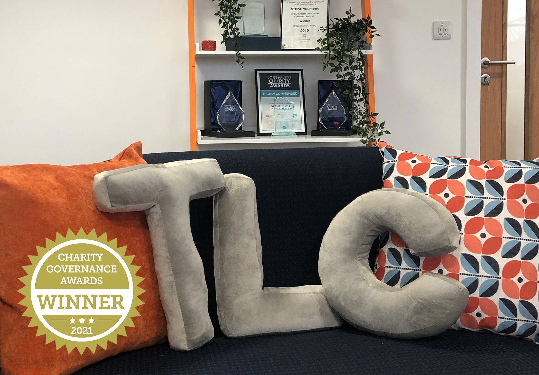 a picture of a couch with TLC shaped cushions with awards behind and a sticker saying charity governance awards WINNER 2021