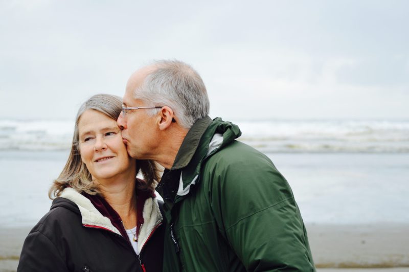 an man kissing an older woman on the head with the seaside in the distance