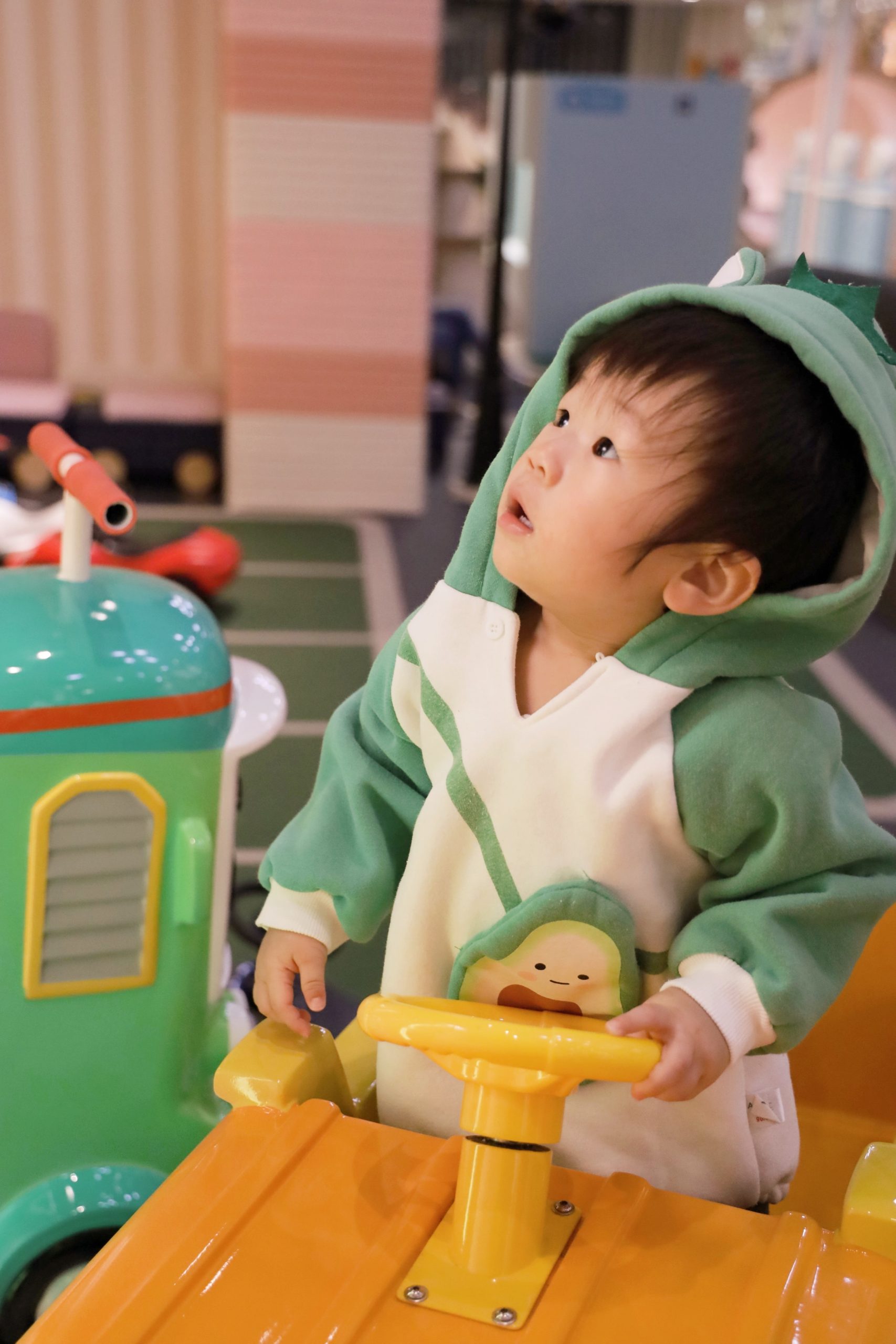 a young boy with a green and cream hoodie staring at something above