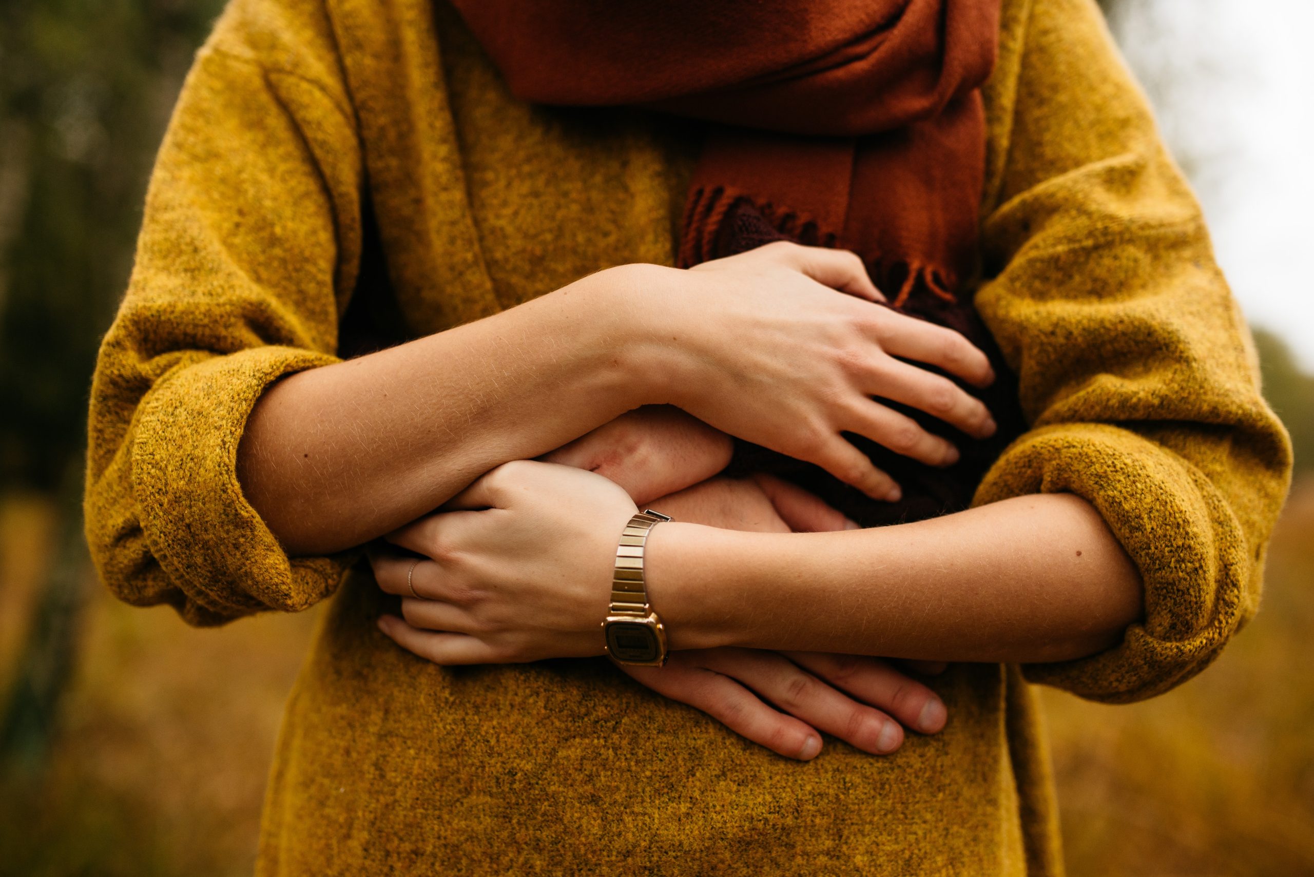 a woman being hugged from behind in a mustard jumper