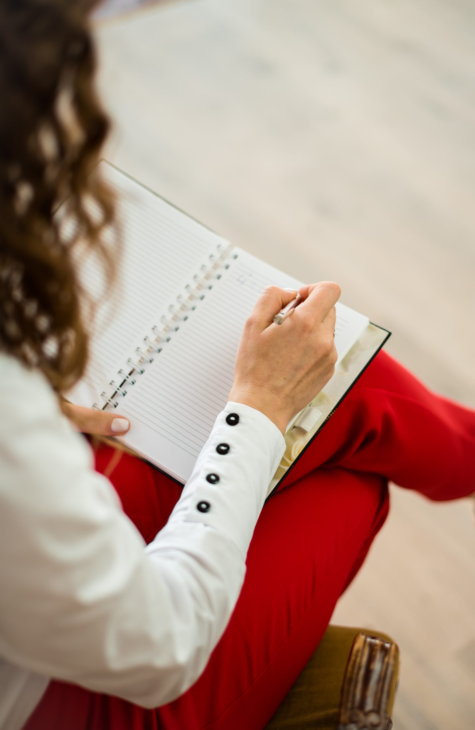 a woman wearing red pants sat down making notes the view from above