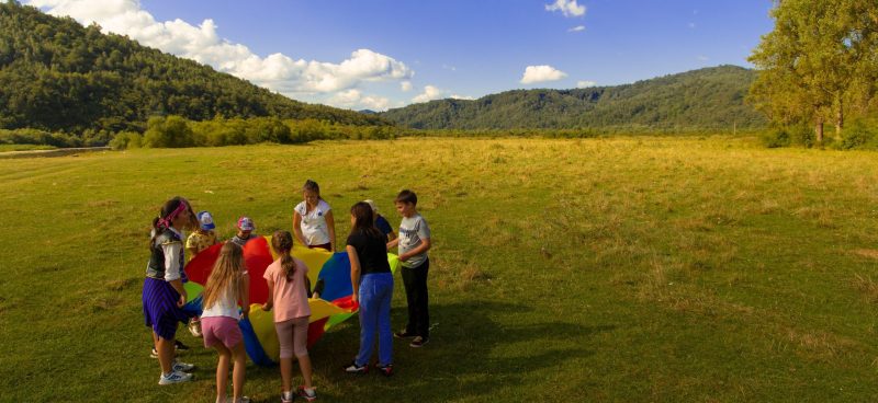 a group of children playing a game with a parachute in the middle of a field