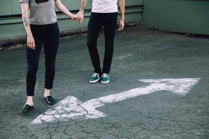 two people holding hands next to a road marking with their face out of the picture