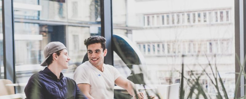 two men sat at a table smiling at each other