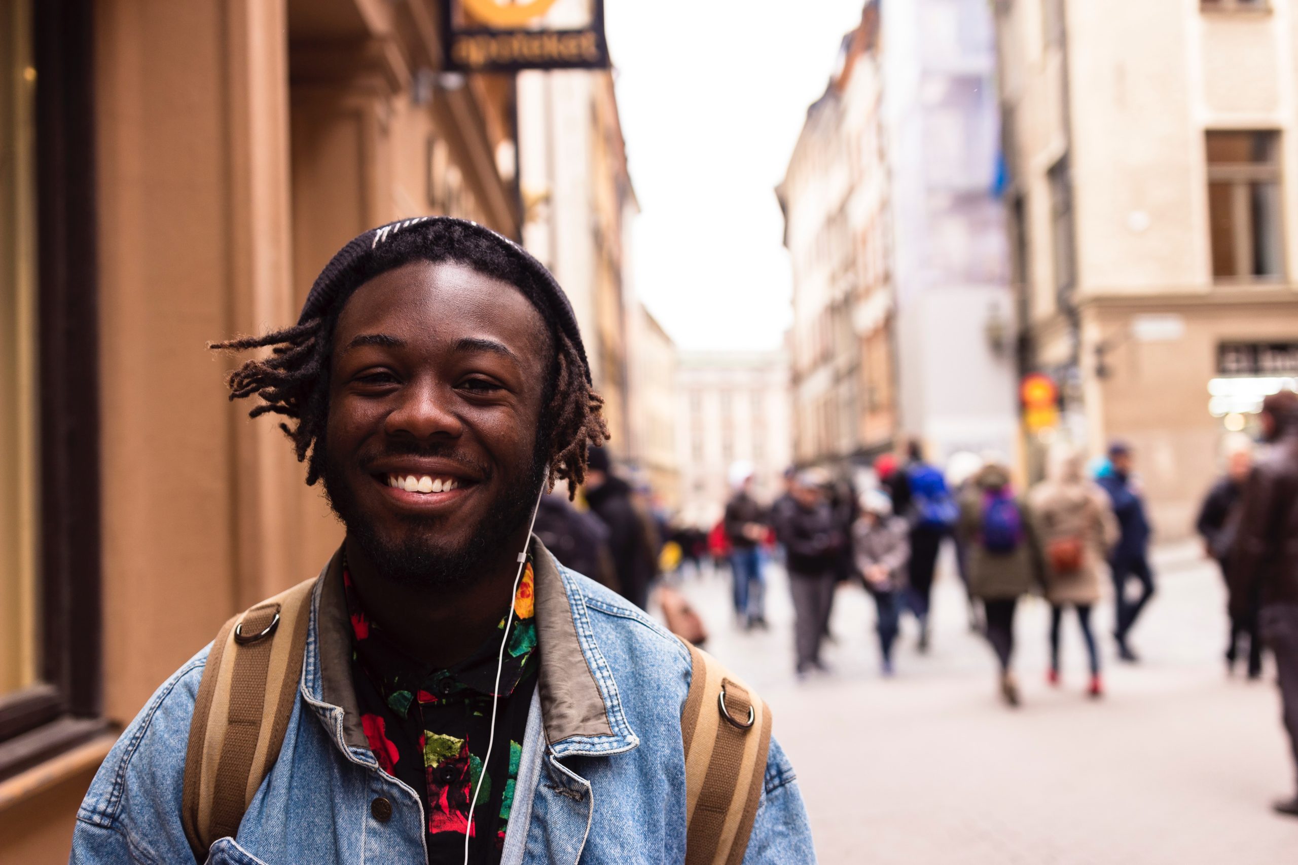 a man walking down a street with earphones in smiling