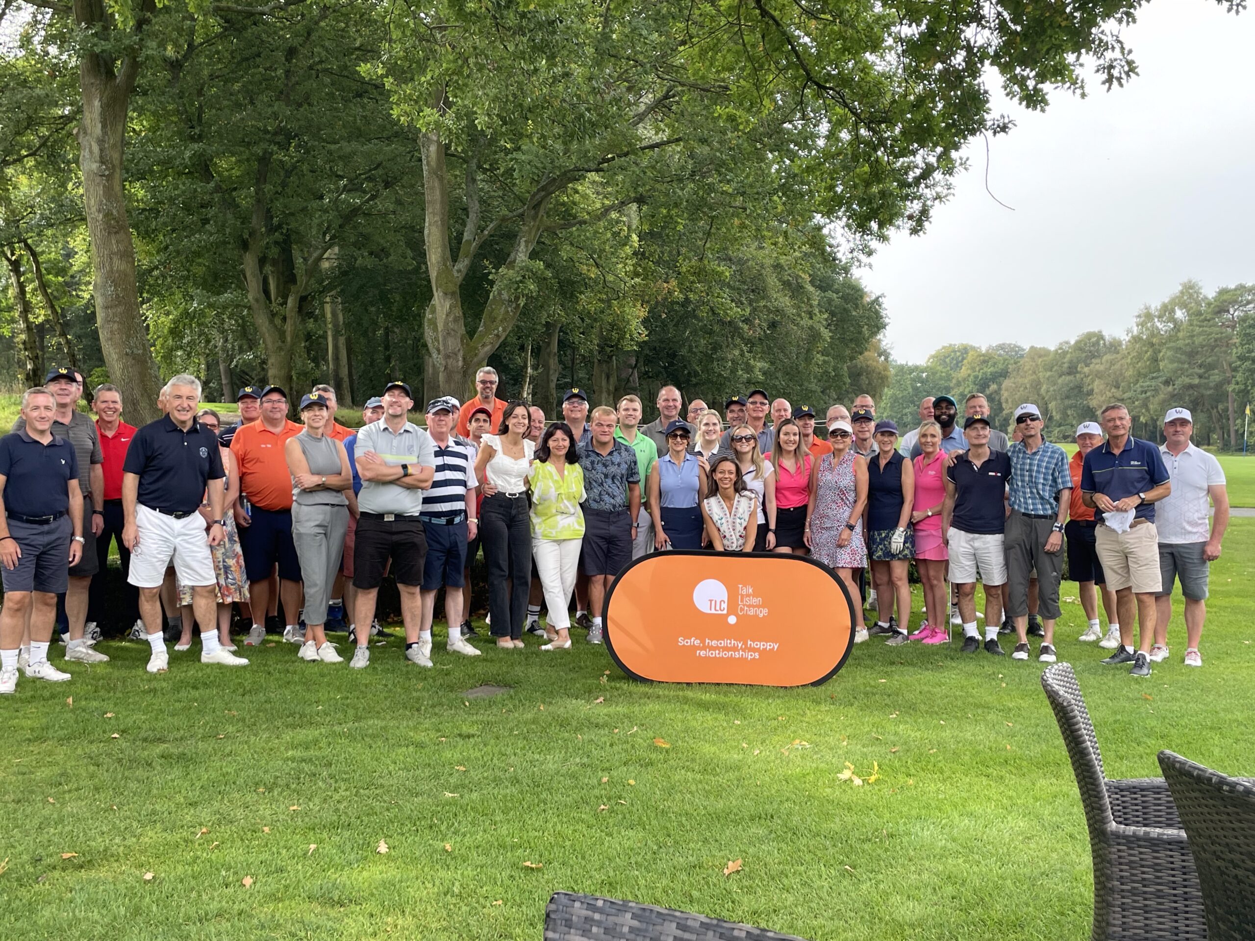large group of people stood posing on a golf course