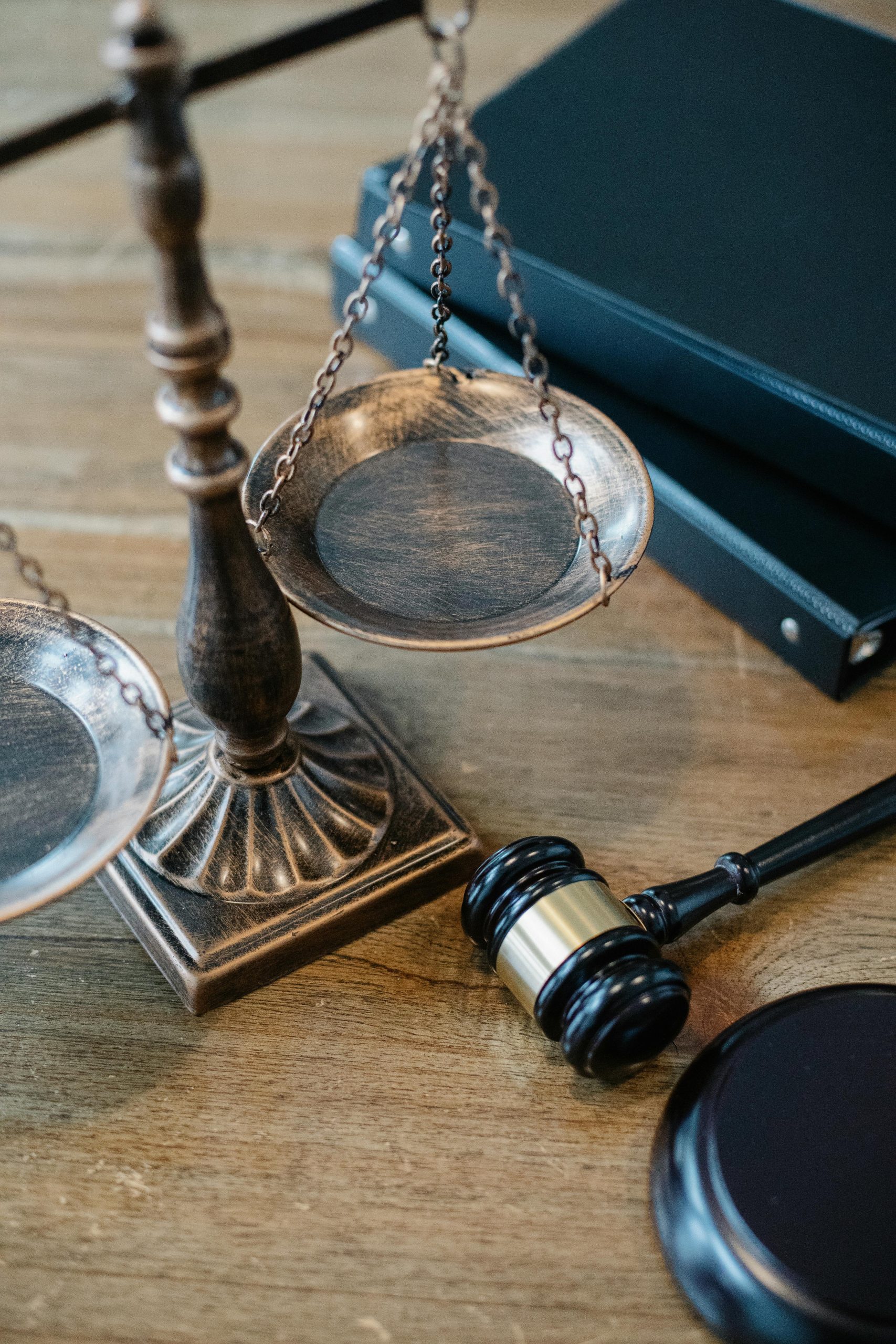 brass weighing scales and gavel on wooden table with files behind