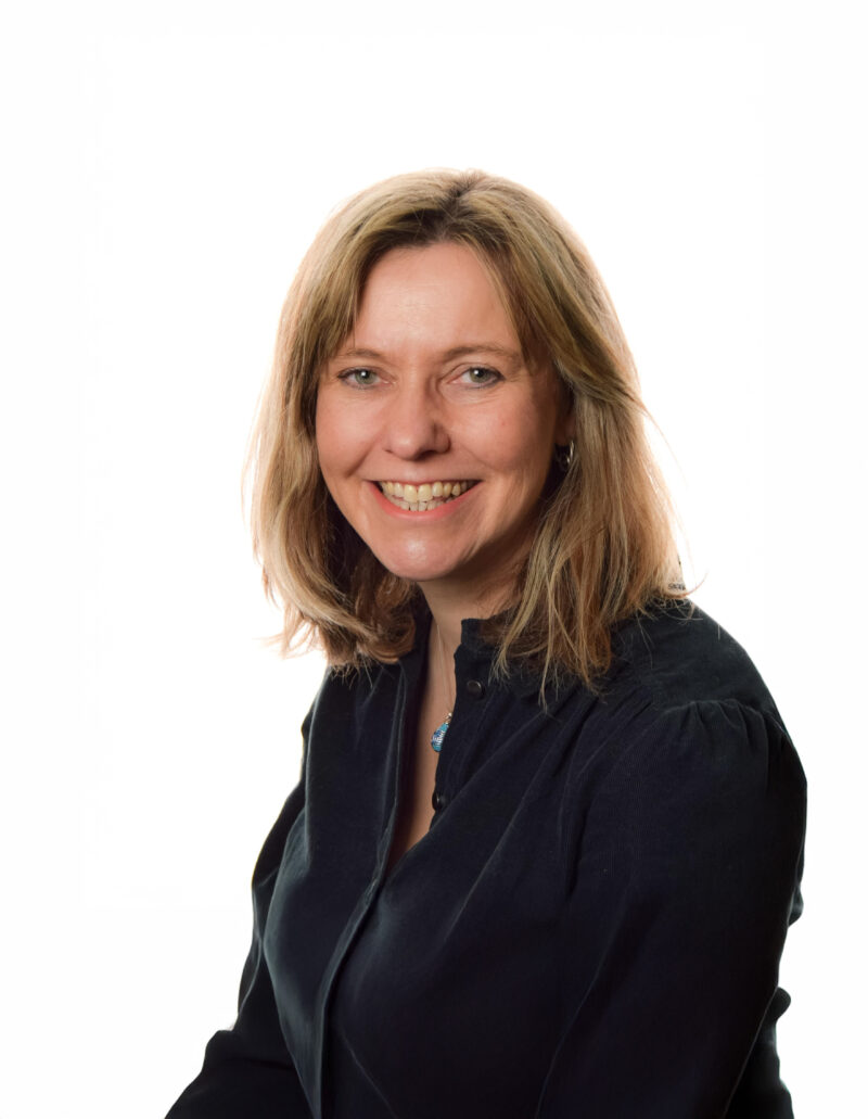 A woman with light brown hair and a black shirt