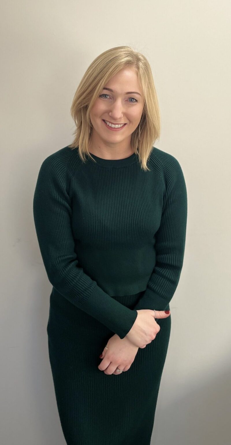 a woman with short blonde hair stood against white background