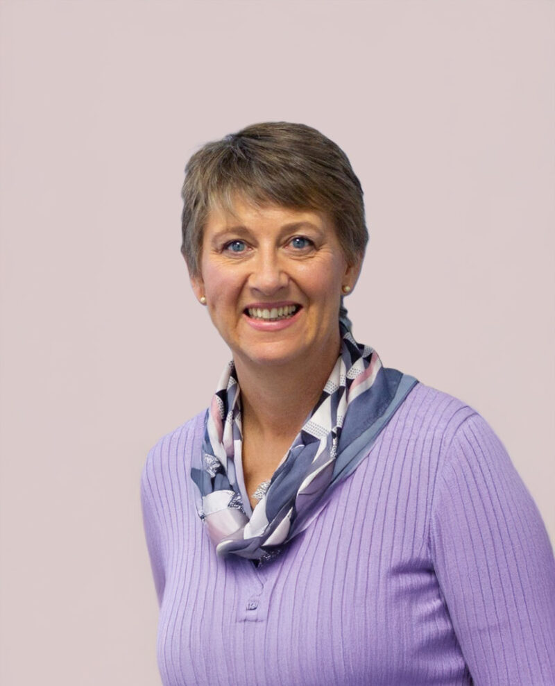 A woman with short hair and a purple knit jumper and a small scarf