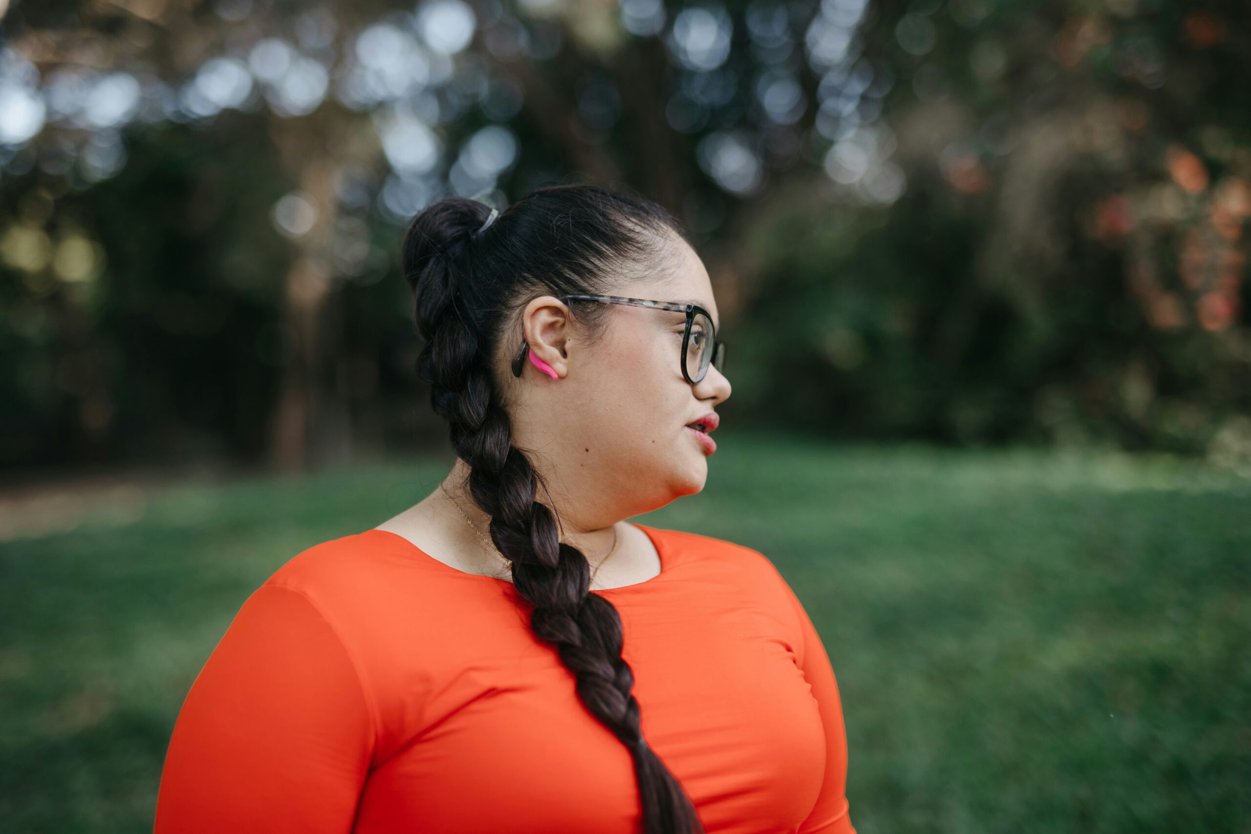 woman with long plaited dark hair looks out over a grassy area. She looks content