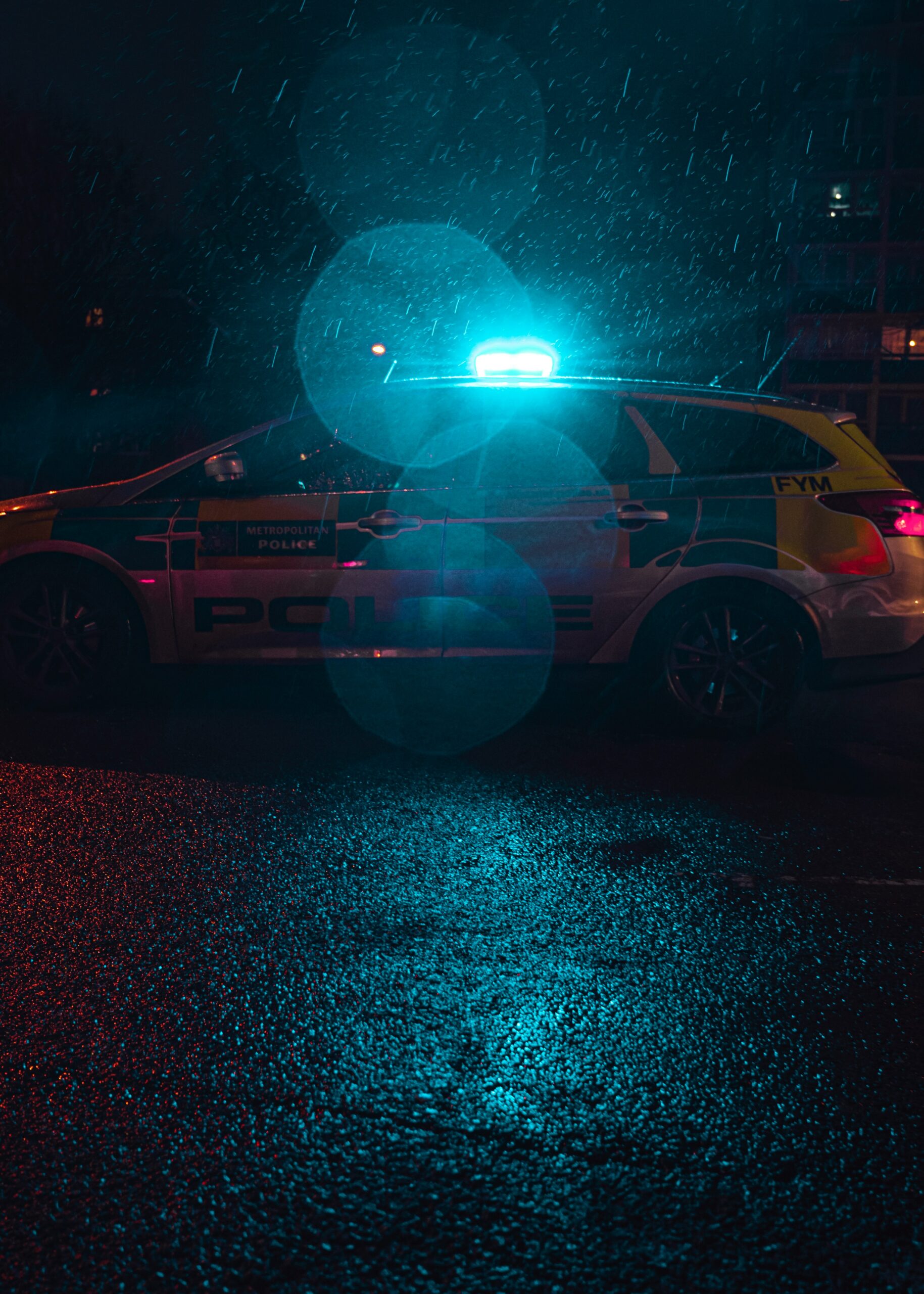 a police car, out of focus, made by emergency blue lights in combination with water droplets on the camera lens