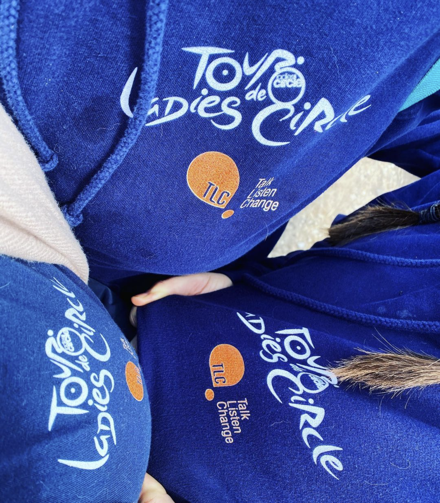 3 people bring blue hoodies into the shot, emphasising the charity logos on them