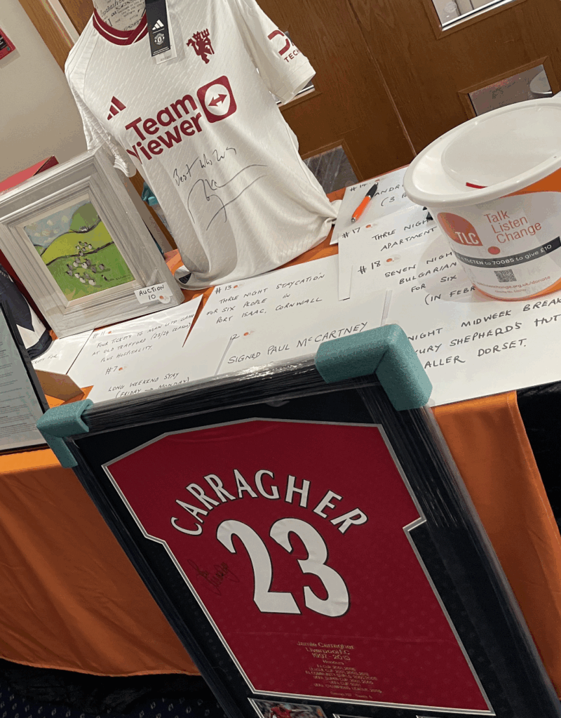 raffle prizes and charity bucket sit on top of a branded table cloth