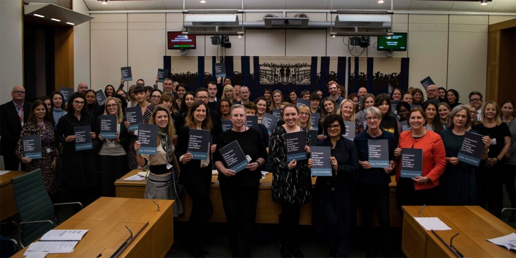 Large group of people who have all signed the 'call to action' document they are showcasing to camera