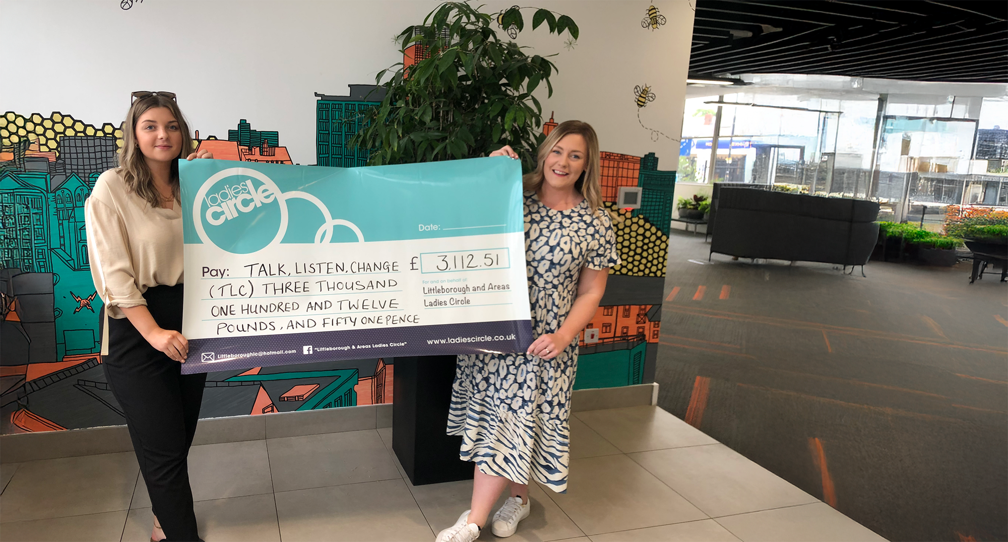 2 people holding a large cheque that is branded LLC